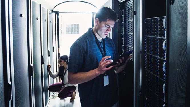 two IT professionals standing next to rows of server racks